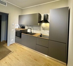 A modern kitchen with grey cabinetry, a built-in oven, and a stainless steel sink. - Casa Magenta Apartment 4 (Valeggio sul Mincio)