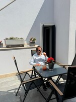 Un hombre sentado en una mesa al aire libre con una planta en maceta y una vela.