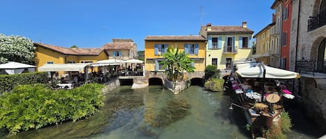 Un canal flanqueado por edificios, un puente y zonas de estar al aire libre.