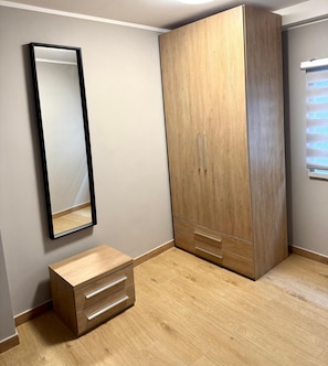 A bedroom with a wardrobe, a mirror, and a bedside table. - Casa Magenta Apartment 4 (Valeggio sul Mincio)