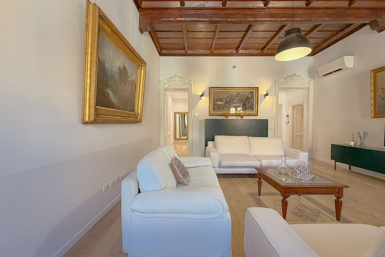 Un salon avec un canapé blanc, une table basse et un tableau accroché au mur.