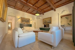 A spacious living area with a high wooden ceiling, white sofas, a green accent wall, and a television. - [Piazza di Spagna] Frattina 14 Luxury Home (Roma)