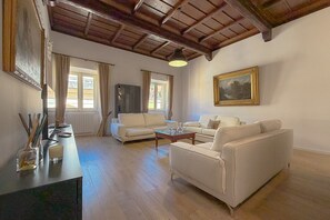 Ein geräumiges Wohnzimmer mit hoher Decke, zwei Sofas, einem Couchtisch und einem Fernseher.