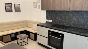 Eine moderne Küche mit Backofen, schwarzem Arbeitsplatz und einem beigefarbenen Sofa.