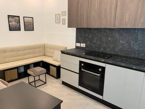 A modern kitchen with a built-in oven, a black countertop, and a beige sofa. - Ground-floor maisonette just steps from the seafront (Tas-Sliema)
