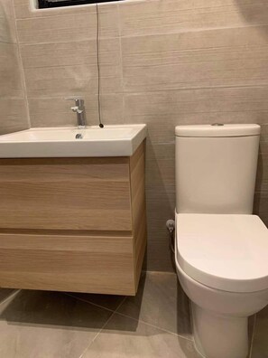 A bathroom with a wooden vanity, a white sink, and a white toilet. - Ground-floor maisonette just steps from the seafront (Tas-Sliema)