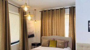 Ein Hotelzimmer mit Bett, Nachttisch, Stuhl und Schreibtisch mit Sitzmöglichkeit.