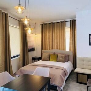 A hotel room with a bed, bedside table, chair, and a desk with a chair. - Ground-floor maisonette just steps from the seafront (Tas-Sliema)