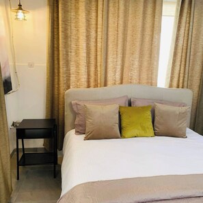 Ein Schlafzimmer mit einem Bett, Kissen, einem Nachttisch und einer Pendelleuchte.