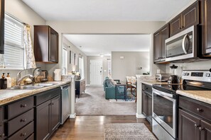 A modern kitchen with dark cabinetry, stainless steel appliances, and a central island. - Roadmap Lodging: Shadow Creek Retreat, 3BR Monthly, Pet OK (Columbus)