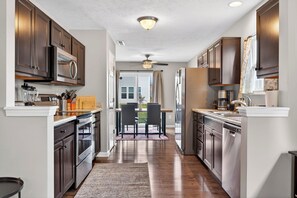 A modern kitchen with dark wood cabinets, stainless steel appliances, and a dining area with a view to the outdoors. - Roadmap Lodging: Shadow Creek Retreat, 3BR Monthly, Pet OK (Columbus)