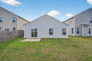 A single-story residential building with a front door, a small patio, and a fenced backyard. - Roadmap Lodging: Single-Level 3BR, Garage, Yard (Columbus)