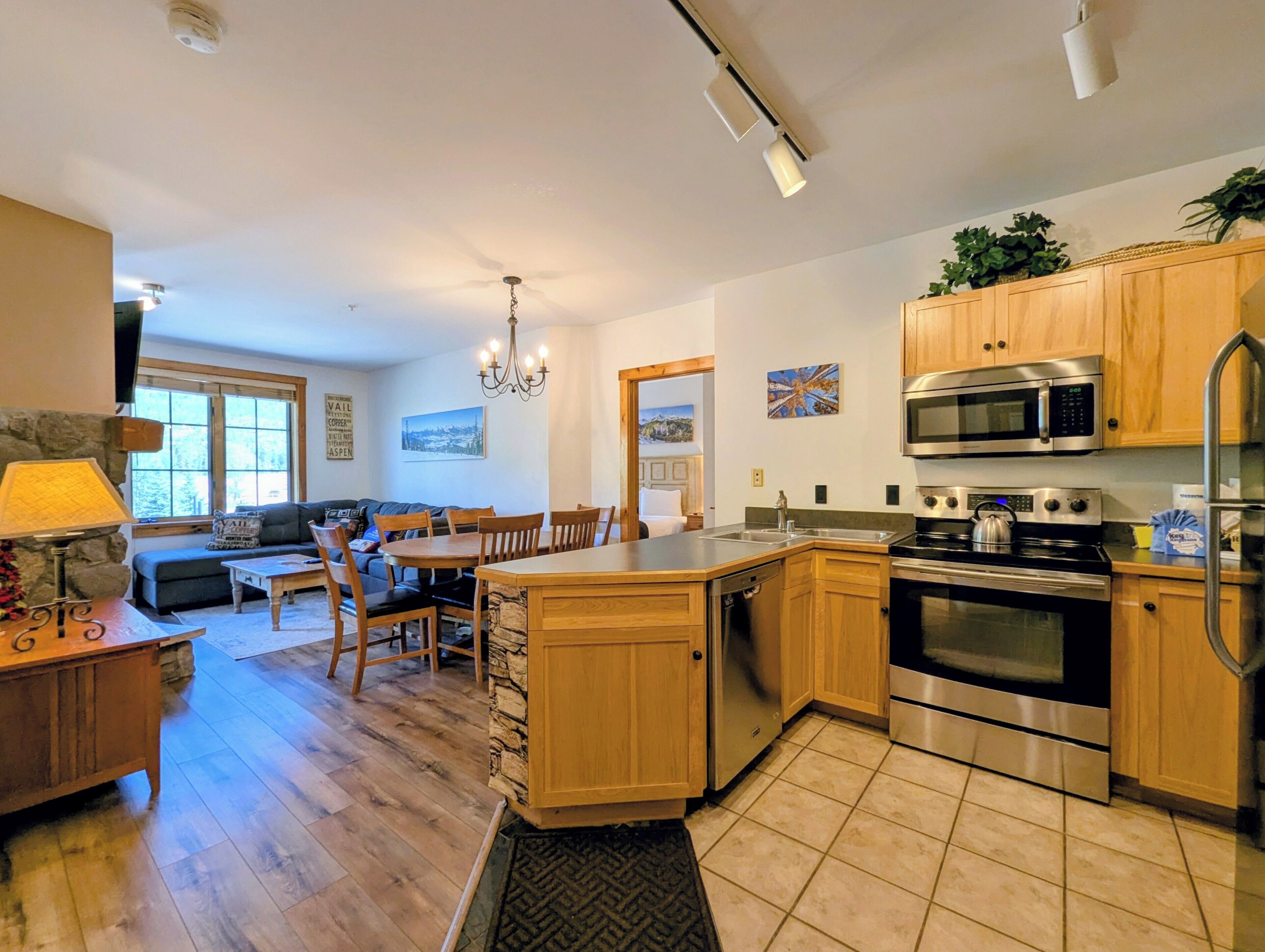 A modern kitchen with wooden cabinets, a stainless steel oven, and a dining area with a table and chairs.