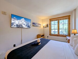 A hotel room with a bed, a window with a view of trees, and two wall-mounted paintings. - Modern Keystone Retreat | Gondola & Hot Tubs (Keystone)