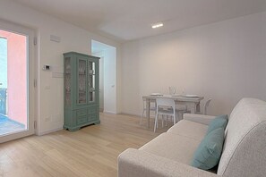 Una sala de estar con un sofá, una mesa de comedor con sillas y un aparador.