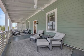 A covered porch with outdoor seating, a ceiling fan, and a view of the street. - Beach House - 4br/3.5 bath home with pool in central Wrightsville Beach! (Wrightsville Beach)