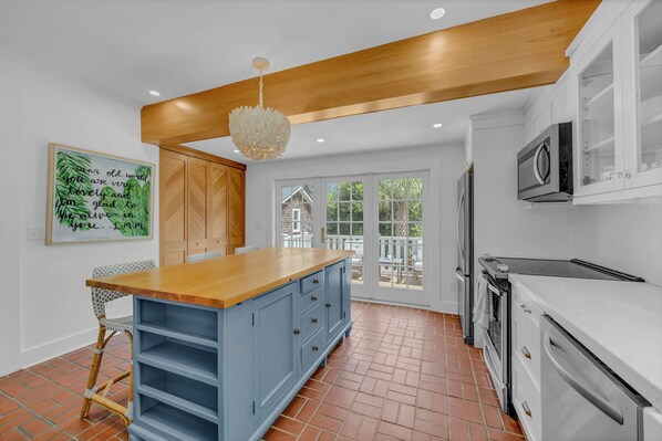 Une cuisine moderne avec un plafond en bois, un îlot central bleu et une vue sur l’extérieur.