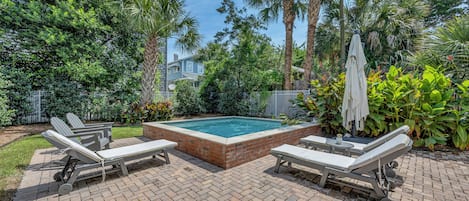 Un área de piscina con sillas de descanso y un solárium de ladrillo.