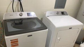 Dues rentadora Maytag en un espai de bugaderia, amb una presa d'electricitat i una caixa elèctrica penjada a la paret.