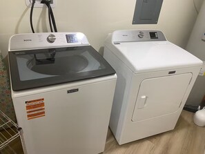 Due lavatrici Maytag in una lavanderia, con una presa di corrente e un quadro elettrico a parete.