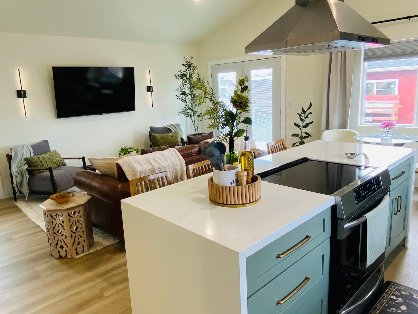 A modern kitchen with a central island, built-in oven, and a dining area with a table and chairs.