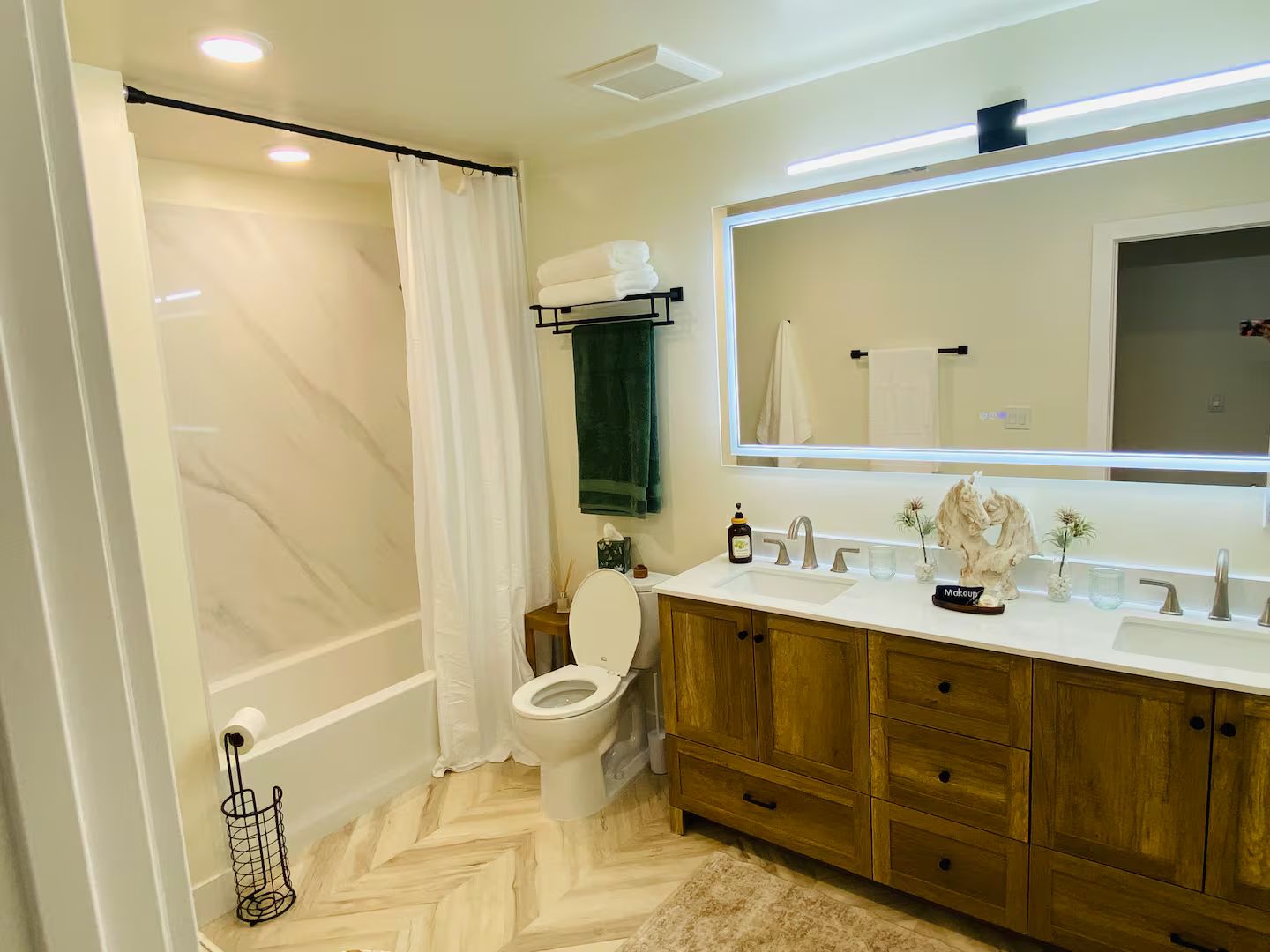 A bathroom with a toilet, a sink with a mirror, wooden cabinets, and a shower area.