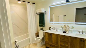 A bathroom with a toilet, a sink with a mirror, wooden cabinets, and a shower area.