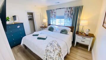 A hotel room with a bed, bedside tables, a wardrobe, and a window with curtains.