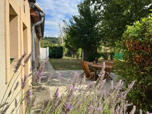A patio with a table and chairs, surrounded by lavender plants.