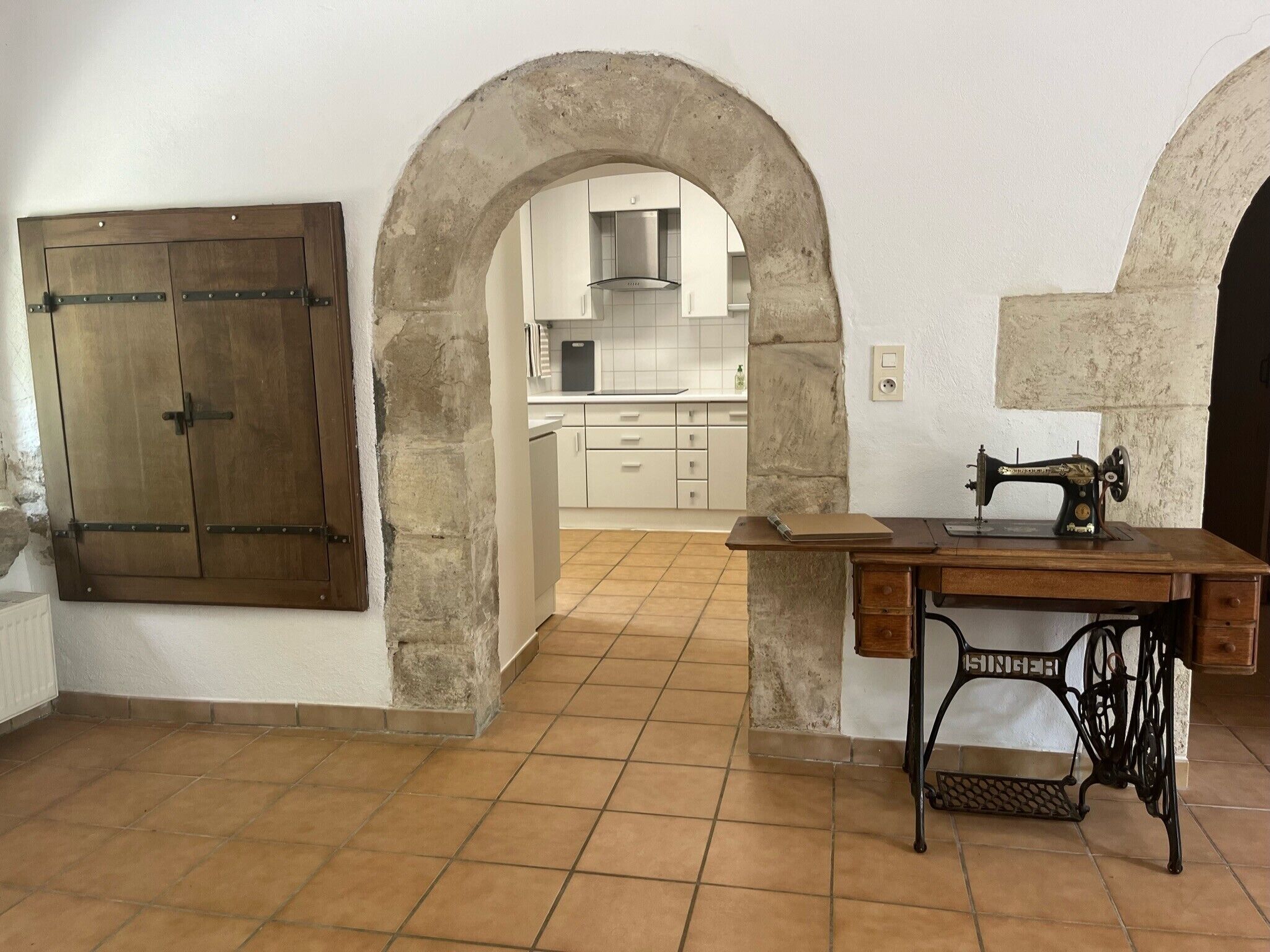 A rustic kitchen with stone walls, a wooden door, and a vintage sewing machine.