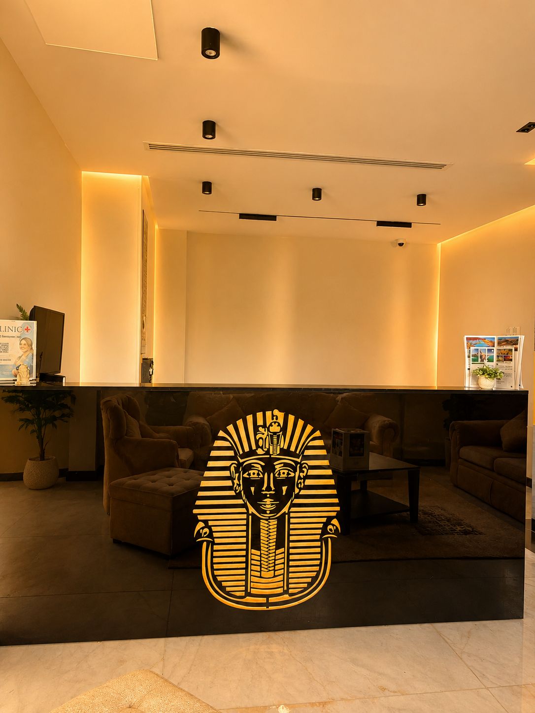 A modern interior with a reception desk, seating area, and a decorative emblem.