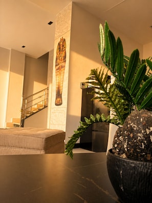A modern interior with a staircase, a wall-mounted Egyptian artifact, and a potted plant. - Casablanca Pyramids View Hotel (Giza)