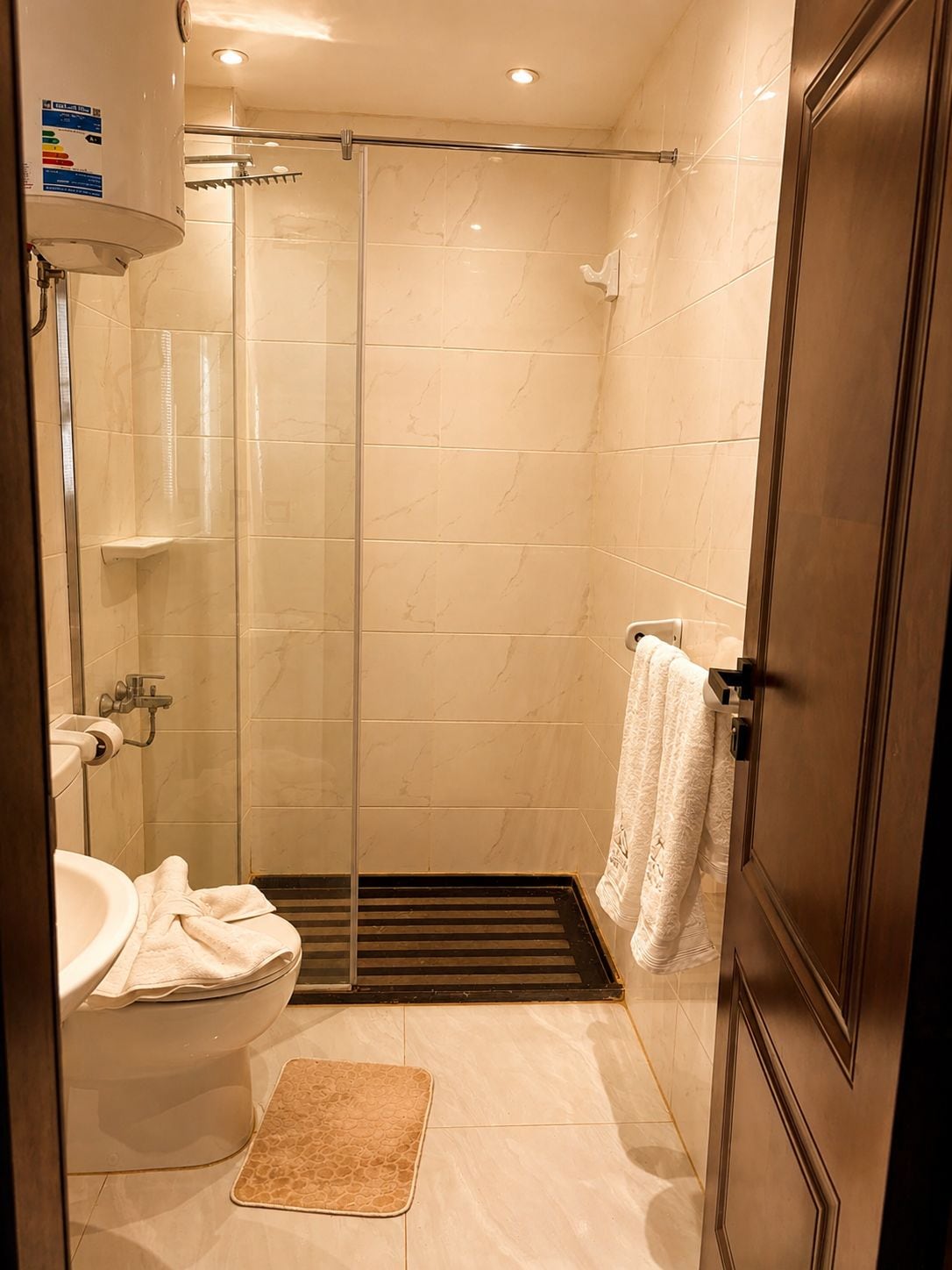 Un baño con ducha de vidrio, inodoro y lavamanos.