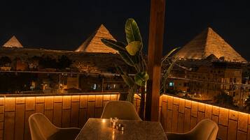 An outdoor seating area with a view of pyramids at night.