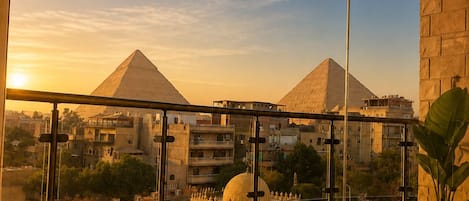 A bathroom with a bathtub, a towel, and a view of pyramids.