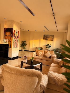 A modern living room with a sofa set, a coffee table, and a decorative pillar with a poster. - Casablanca Pyramids View Hotel (Giza)