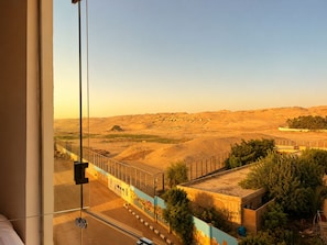 A room with a large window overlooking a desert landscape with a fence and greenery. - Casablanca Pyramids View Hotel (Giza)