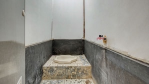 Un baño pequeño y cerrado con bañera, secamanos y suelo de baldosas.