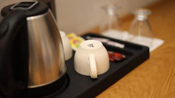 Una bandeja con una cafetera, dos tazas blancas, un recipiente de vidrio y un sobre de azúcar.