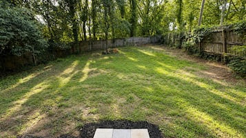 A backyard with a grassy lawn, a wooden fence, and trees.