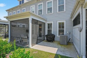 Ein überdachter Patio-Bereich mit Sitzgelegenheiten und einem Grill.