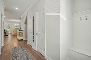 A hallway with white walls, wooden flooring, and a patterned rug. - New on Program! The Townes at Barefoot #5202! Your Favorite Place to Golf! (North Myrtle Beach)