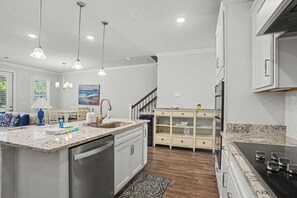 A modern kitchen with a central island, stainless steel appliances, and pendant lighting. - New on Program! The Townes at Barefoot #5202! Your Favorite Place to Golf! (North Myrtle Beach)
