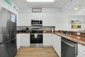 Eine moderne Küche mit Edelstahlgeräten, weißen Schränken, Granitarbeitsplatten und Holzboden.