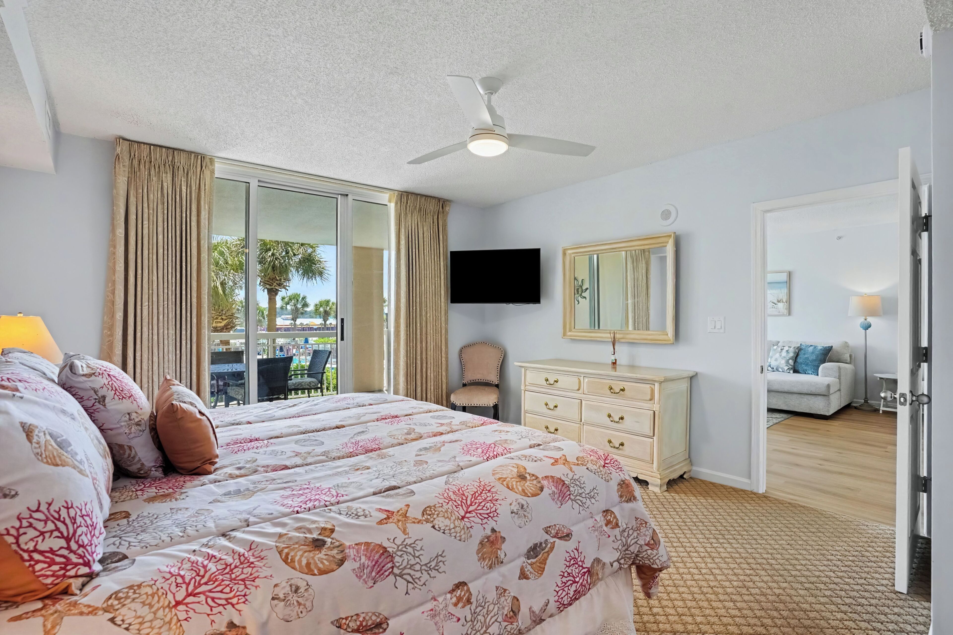 A hotel room with a bed, a television, a dresser, and a view of the outdoors.