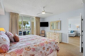 A hotel room with a bed, a television, a dresser, and a view of the outdoors. - New Property On Program! North Tower #207 in Barefoot Resort! (North Myrtle Beach)