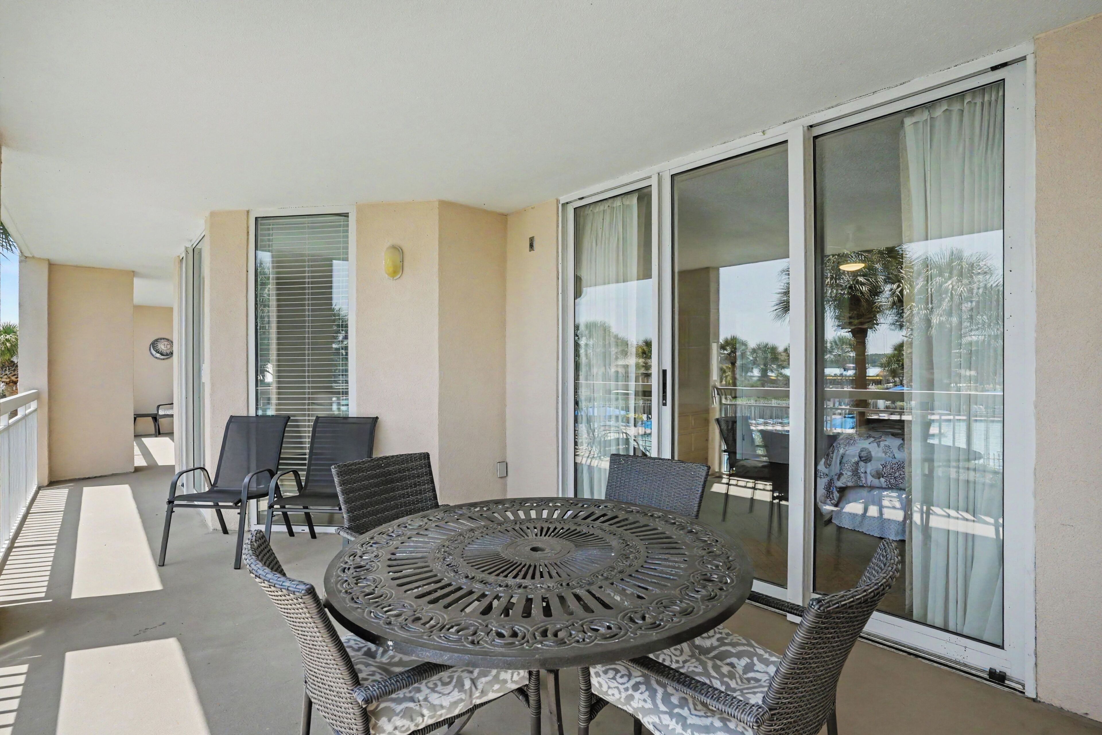 Un balcon avec une table ronde et des chaises, de grandes portes-fenêtres coulissantes et une vue sur l’extérieur.