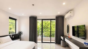 A modern bedroom with a bed, a TV, a fan, and a balcony with curtains. - Hoang Linh Hotel Phu Quoc (Phu Quoc)