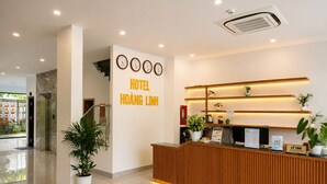 A hotel reception area with a reception desk, wall clocks, and a sign reading 'HOTEL HOÀNG LINH'. - Hoang Linh Hotel Phu Quoc (Phu Quoc)