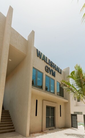 Een gebouw met het bord 'Walishali Gym', wat een fitnesscentrum aangeeft.